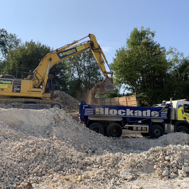 Blockade digger and lorry on demolition site